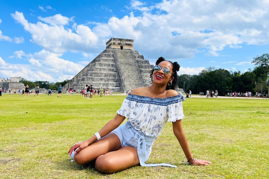Traveller sat smiling by Chichen Itza in Mexico