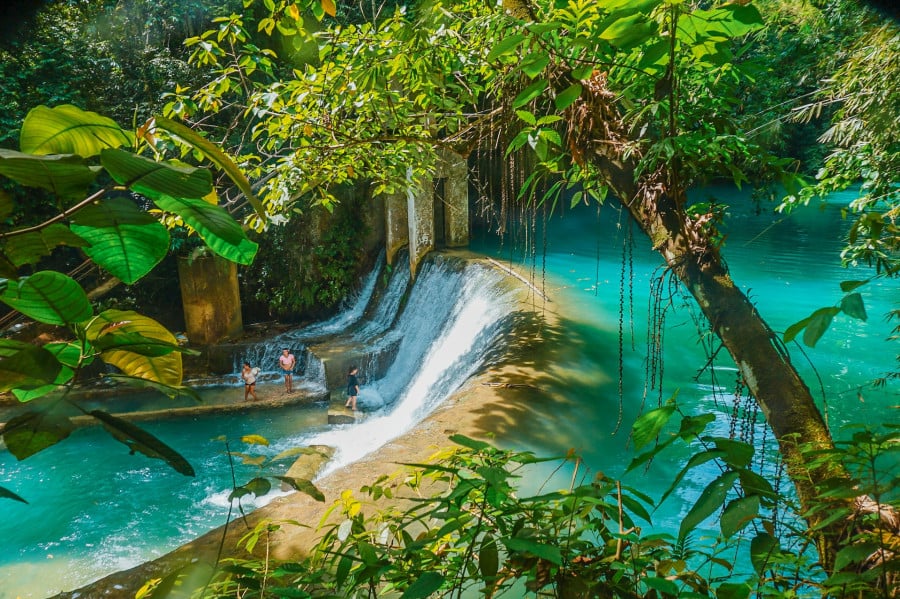 Bright turquoise river leading into small waterfall and surrounded by tropical green jungle